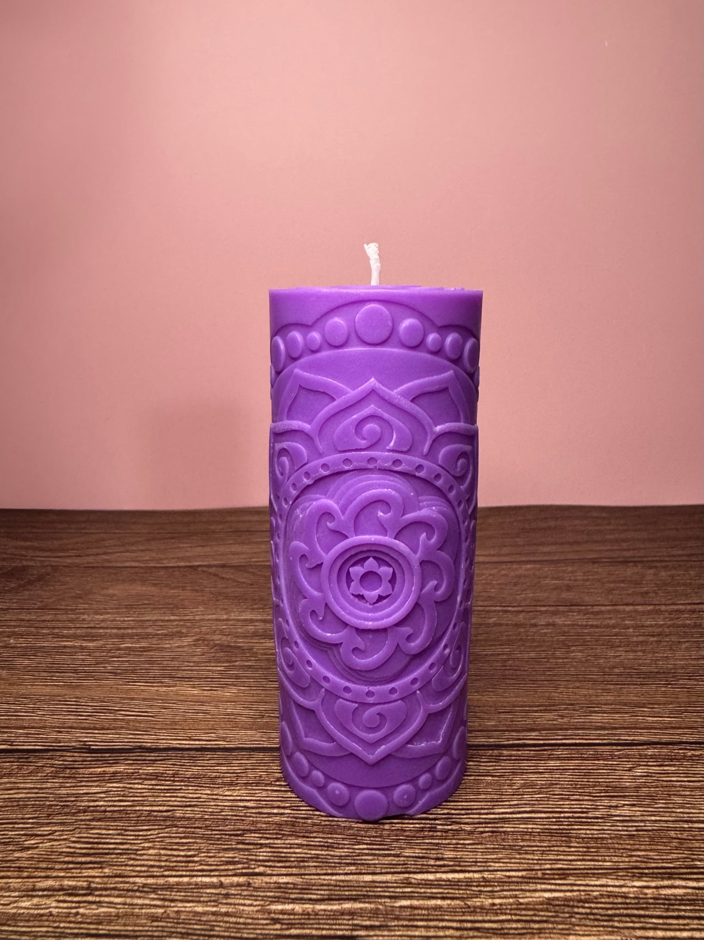 candela artigianale viola in cera di soia e disegno mandala del rituale la fiamma della quiete su base si legno con sfondo rosa