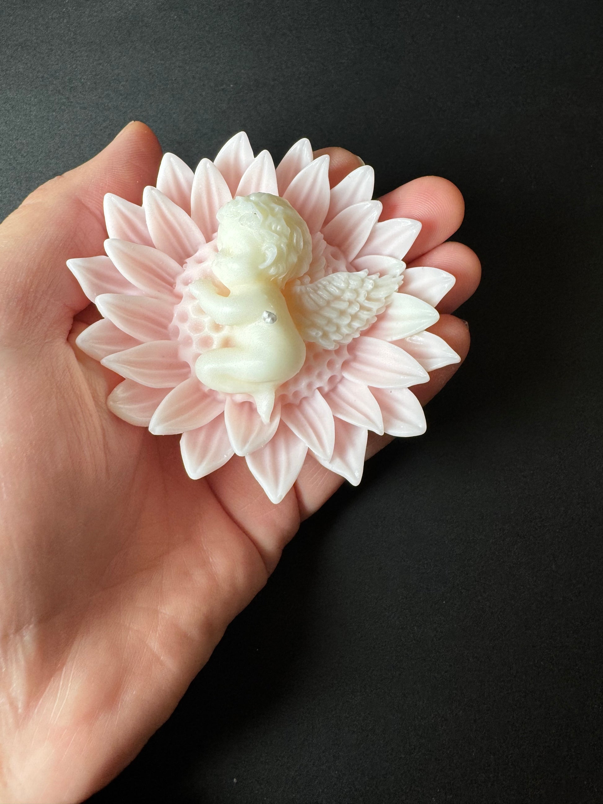 mano che tiene candela fiore con angioletto