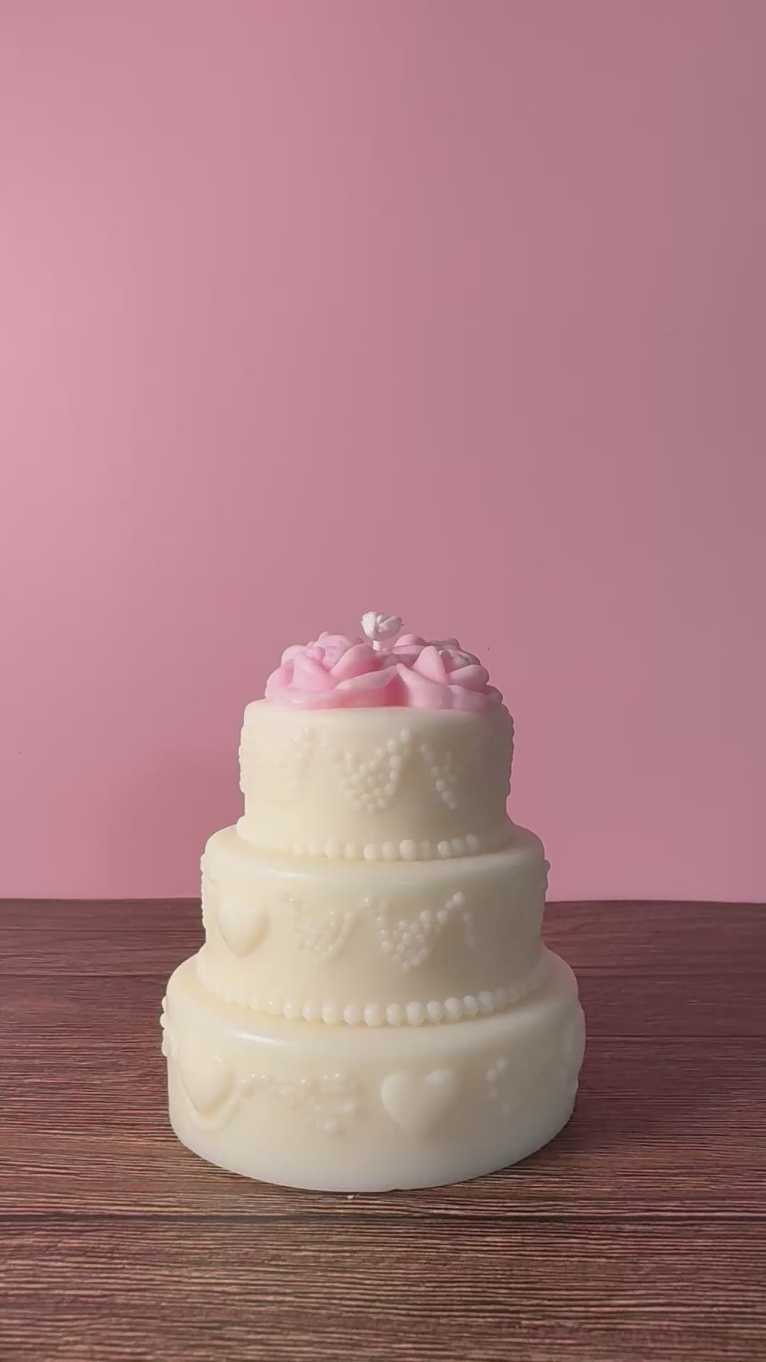 candela a forma di torta a tre piani decorativa con fiori sulla parte superiore e decorazioni sui lati